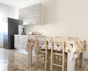 a kitchen with a table with chairs and a refrigerator at Le Rose Apartment in Ortona