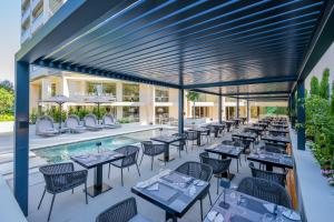 een terras met tafels en stoelen en een zwembad bij Divani Escape in Athene