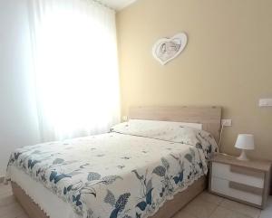 a bedroom with a bed and a heart clock on the wall at Le Rose Apartment in Ortona