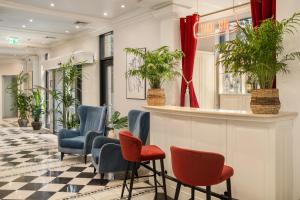 a waiting area in a lobby with chairs and plants at Queen's Court Hotel & Residence in Budapest