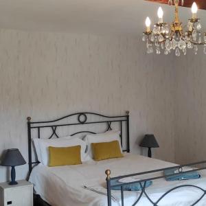 a bedroom with a bed with yellow pillows and a chandelier at Moulin des Prés - 15 couchages - 1h15 des Jeux Olympiques PARIS 2024 in Croissy-sur-Celle