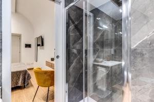 La salle de bains est pourvue d'une douche avec une porte en verre. dans l'établissement Domus Partenopea, à Naples