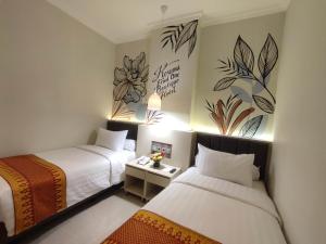 巨港的住宿－Kesuma Front One Boutique Palembang，酒店客房设有两张床,墙上挂有绘画作品