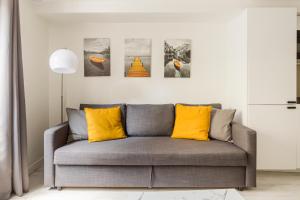 a living room with a gray couch with yellow pillows at Design 1 BDR with AC in Paris