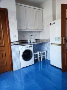 a kitchen with a white refrigerator and a washing machine at Apartamento acolhedor Oeiras in Barcarena