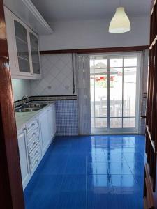 cocina con suelo de baldosa azul y ventana grande en Apartamento acolhedor Oeiras, en Barcarena