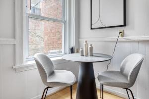 a table and chairs in a room with a window at Cozy N End 1BR steps from Harborwalk BOS-446 in Boston