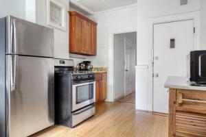 a kitchen with a stainless steel refrigerator and wooden cabinets at Cozy N End 1BR steps from Harborwalk BOS-446 in Boston