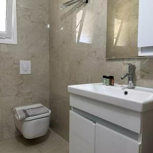 a white bathroom with a sink and a toilet at Vila Zisi Himare in Himare