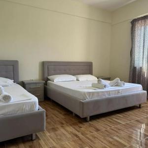 two twin beds in a room with wooden floors at Vila Zisi Himare in Himare