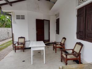eine Terrasse mit 2 Stühlen und einem weißen Tisch in der Unterkunft Shine Breeze villa in Weligama
