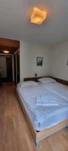 a bedroom with a large white bed with a ceiling at Hotel Stadthof Glarus in Glarus