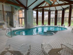 a large swimming pool with chairs in a building at Le petit Nid Rouge in Ustou