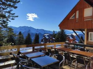 a group of tables and chairs on a deck with mountains at Le petit Nid Rouge in Ustou