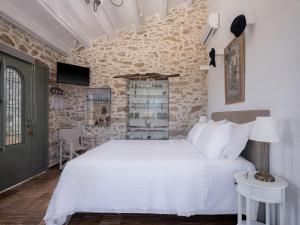 a bedroom with a white bed and a stone wall at Ondathaki Pirgos in Pírgos Psilonérou