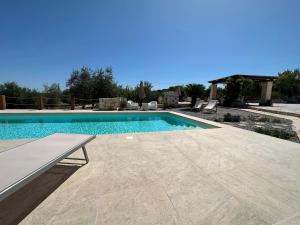een zwembad met een bank in een tuin bij Trulli Santa Maria Odegitria Relais in Ostuni