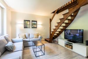 een woonkamer met een bank en een tv bij Wonderful house in Sarlat center with heated pool & jaccuzi in Sarlat-la-Canéda