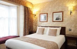 um quarto de hotel com uma cama grande e uma janela em The Bell Hotel Woburn By Greene King Inns em Woburn