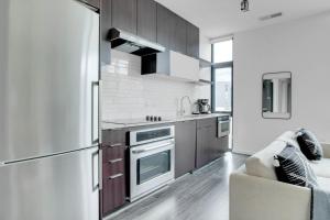 a kitchen with a stainless steel refrigerator freezer next to a couch at Shaw 1BR w Gym WD Rooftop nr U St bars WDC-560 in Washington