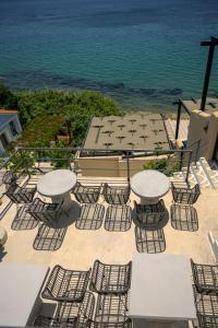 un grupo de mesas y sillas con el océano en el fondo en Olive Green Studios and Apartments en Plomari