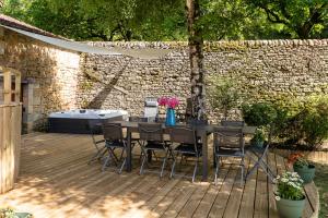 een patio met een tafel en stoelen op een houten terras bij Wonderful house in Sarlat center with heated pool & jaccuzi in Sarlat-la-Canéda