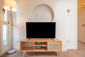 a flat screen tv sitting on top of a wooden entertainment center at The Aristocrat - Fitzrovia - by Frankie Says in London