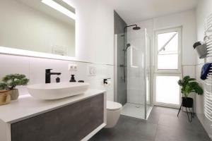 ein weißes Badezimmer mit Waschbecken und Dusche in der Unterkunft Appartementhaus kleines Glück &MeineCardPLUS in Willingen