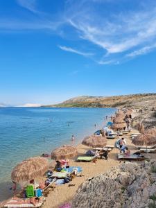 a group of people laying on a beach with umbrellas at Apartments Loncar-near Zrće beach in Novalja