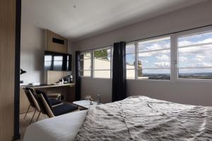 um quarto com uma cama, 2 cadeiras e janelas em Hôtel & Restaurant Origines par Adrien Descouls - Teritoria em Issoire