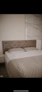 a bedroom with a white bed with a wooden headboard at Luxury Apartment in Lukavac