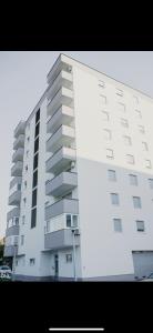 een groot wit appartementencomplex met een parkeerplaats bij Luxury Apartment in Lukavac