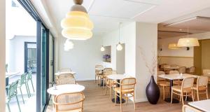 een restaurant met tafels en stoelen en een vaas bij Best Western Kemaris in Biarritz