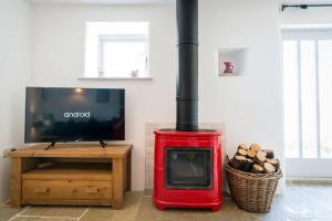 a red wood stove in a living room with a tv at Hilltop Farm - Middle Barn luxury accommodation in Tansley