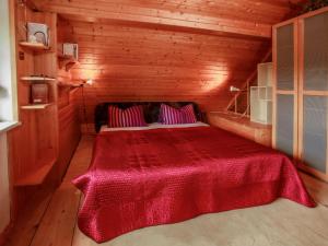 een slaapkamer met een rood bed in een houten hut bij Chalet Karasova II - DEH102 by Interhome in Dehtáře