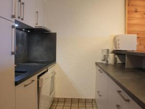 a kitchen with white cabinets and a black counter top at Apartment Ambassadeur 15 by Interhome in Villars-sur-Ollon