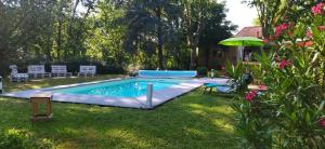 einen Pool in einem Garten mit Stühlen und einem Sonnenschirm in der Unterkunft Au Bois de la Grave in Luzech
