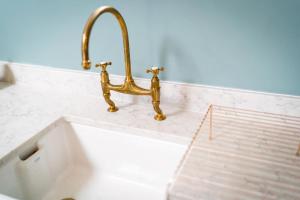 a sink with a gold faucet on a counter at Hilltop Farm - Middle Barn luxury accommodation in Tansley