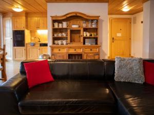 Apartment Daphné A 32 by Interhome في فيلار سور أولون: أريكة جلدية سوداء مع وسائد حمراء في مطبخ