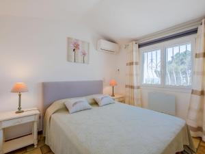a bedroom with a white bed and a window at Villa Clos Romain by Interhome in Les Issambres