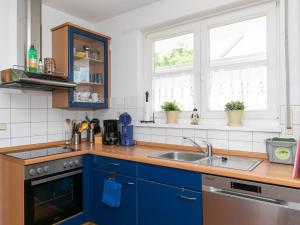 ZudarにあるHoliday Home Losentitz-2 by Interhomeの青いキャビネットとシンク付きのキッチン、2つの窓