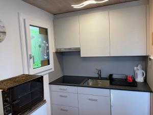 una cocina con armarios blancos y fregadero en Chalet Margrith by Interhome, en Oberwilen