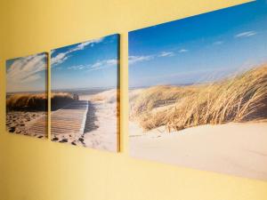 drie schilderijen van een strand met een promenade naar het zand bij Apartment Am Strom-3 by Interhome in Ummanz