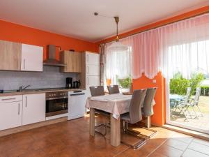 een keuken met een tafel en stoelen en een keuken met oranje muren bij Apartment Am Strom-3 by Interhome in Ummanz
