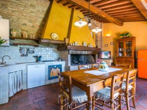 Holiday Home Casa Mori by Interhome في Vico dʼElsa: مطبخ مع طاولة خشبية مع كراسي وموقد
