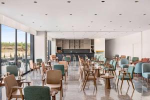 Ramada Plaza By Wyndham Batman في بطمان: غرفة طعام مع طاولات وكراسي ونوافذ