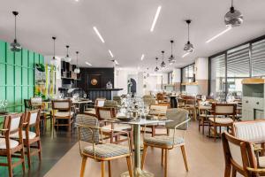 Ramada Plaza By Wyndham Batman في بطمان: مطعم فيه طاولات وكراسي في الغرفة