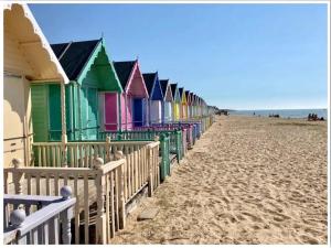 a row of colorful beach huts on the beach at The Mariners Suite in West Mersea