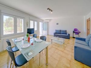 a living room with a glass table and blue chairs at Apartment Gavrena by Interhome in Fanadix