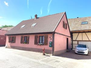 a pink building with a car parked in front of it at Aux deux hirondelles in Houssen