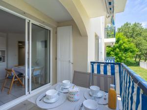 une table avec des tasses et des soucoupes sur un balcon dans l'établissement Apartment Parc de Pontaillac-21 by Interhome, à Pontaillac